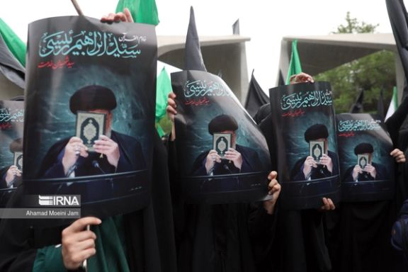 People holding photos of late president Ebrahim Raisi during an event to honor him in front of the university of Tehran, May 2024