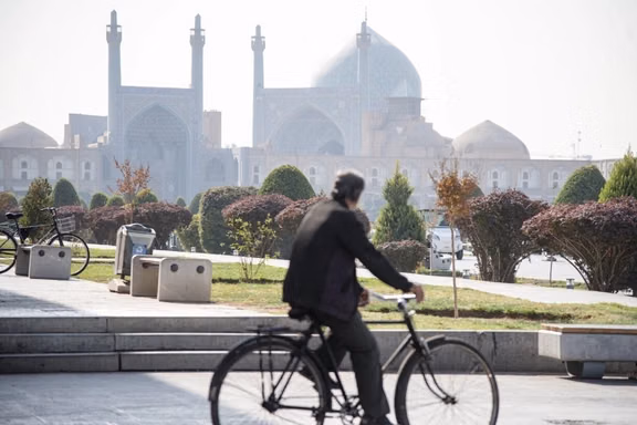 A man riding a bicycle stares at the grand mosque (known both as the Shah Mosque and the Imam Mosque), in Isfahan's historic Naqsh-e Jahan square, Iran, November 2025