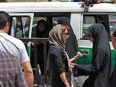 A woman with headscarf stopped by morality police and being asked to go into police van in Tehran