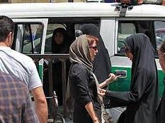 A woman with headscarf stopped by morality police and being asked to go into police van in Tehran