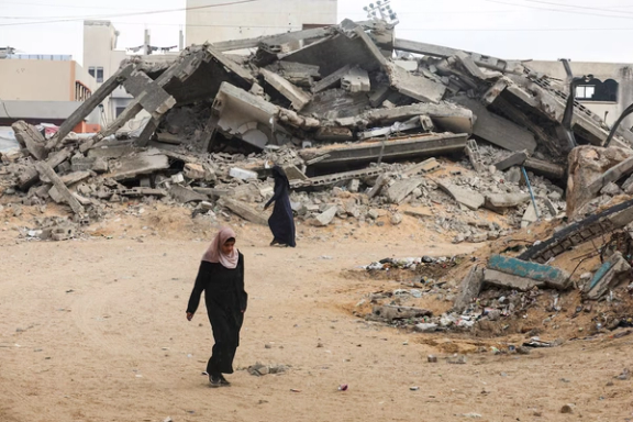 Palestinian women walk near rubble after a ceasefire, in Khan Younis in the southern Gaza Strip, October 9.