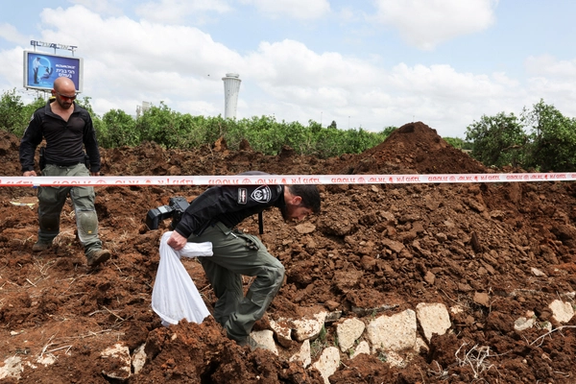 Israeli police officers investigate a crater at the site of a missile attack, launched from Yemen, near Ben Gurion Airport, in Tel Aviv, Israel May 4, 2025.