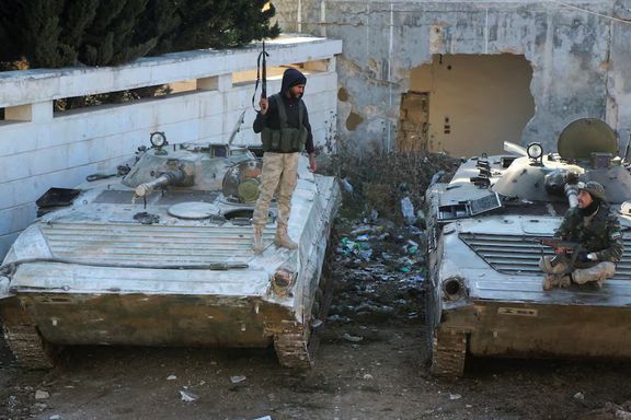 Rebel fighters talk together as one of them stands on a military vehicle holding a weapon in the town of Tel Rifaat, Syria December 2, 2024.