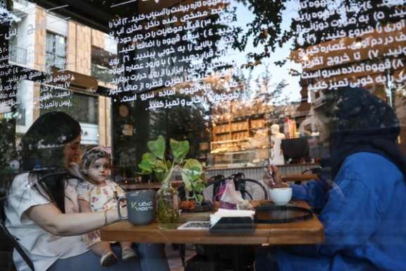 Two young woman and a child sit inside a café in Tehran, May 11, 2026