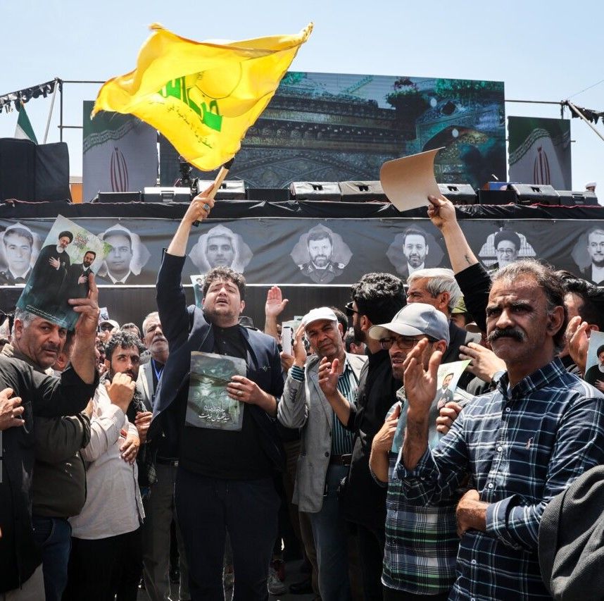 یکی از حاضران در مراسم تشییع رئیسی در حال تکان دادن پرچم حزب‌الله، مشهد، سوم خرداد