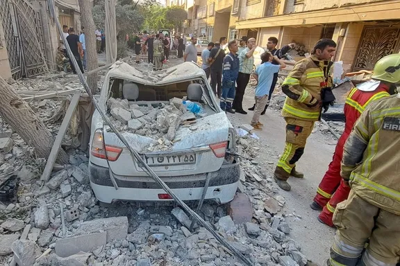Firefighters with an aerial truck approaching a building destroyed in Israeli airstrikes on Tehran