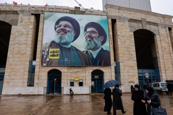 People pass a banner near Camille Chamoun Sports City Stadium during preparations for the funeral of former Hezbollah leader Hassan Nasrallah who was killed in Israeli airstrikes last year in Beirut, Lebanon February 22, 2025.