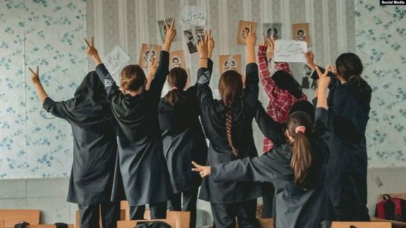 A group of schoolgirls unveiling in their classroom after tearing photos of the founder of the Islamic Republic Ruhollah Khomeini