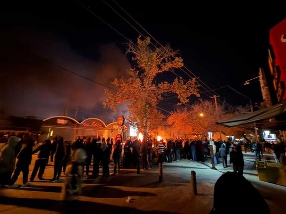 Protesters gather on Afifabad Street in Shiraz on January 8, 2025 as flames rise in the background during overnight unrest.