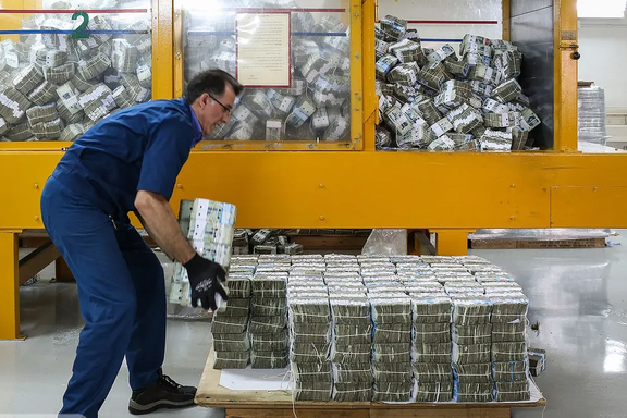 A worker stacks bundles of old Iranian banknotes