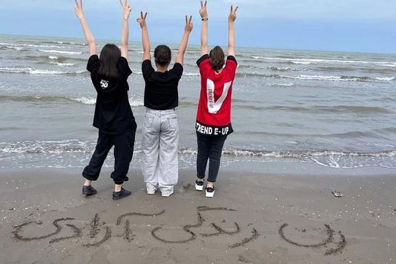 Young Iranian women without hijab challenge the regime. Writing on the sand says, "Woman, Life, Freedom"