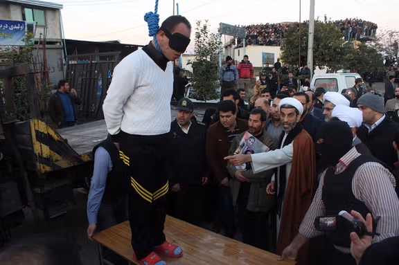 A blindfolded man stands on a platform moments before his public execution in Iran (Undated)