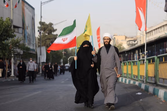 A cleric and his wife carry Iranian and Hezbollah flags as they attend a gathering to support Iran's Armed Forces after US President Donald Trump announced a ceasefire between Israel and Iran, in Tehran, Iran, June 24, 2025.