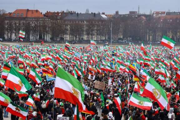 A large gathering of Iranians in Munich, Germany, in February 2026, with participants waving Lion and Sun flags.