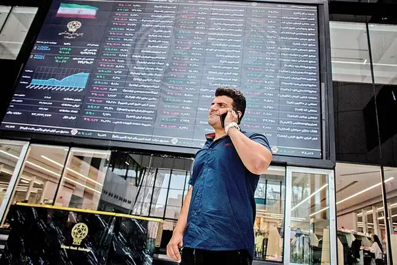 File photo: A man speaks on his phone beneath a market board at the Tehran Stock Exchange.