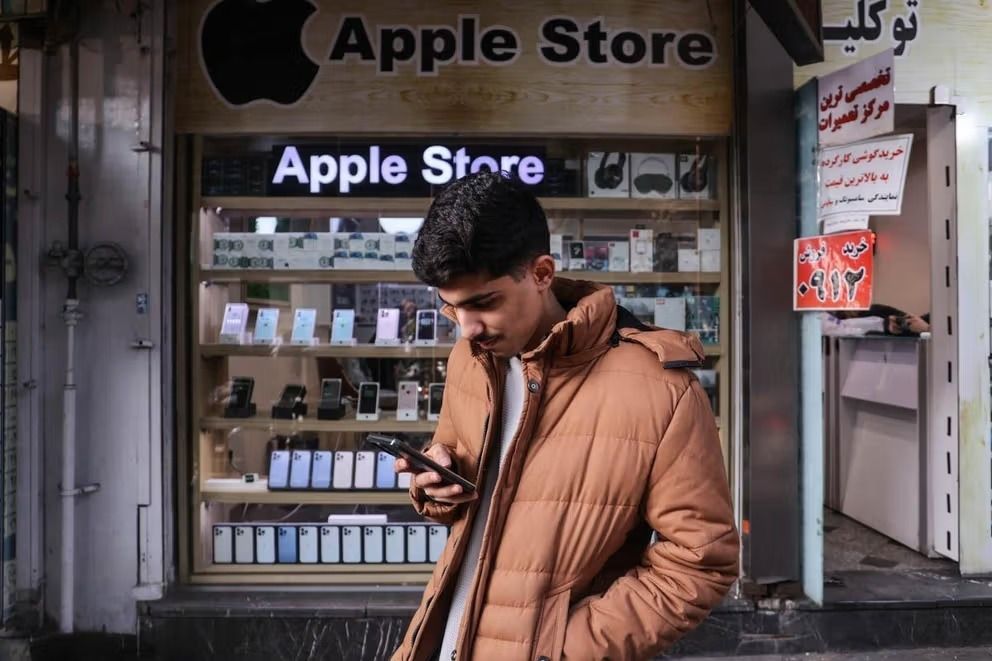 File photo of a young Iranian man who checks his phone outside a store