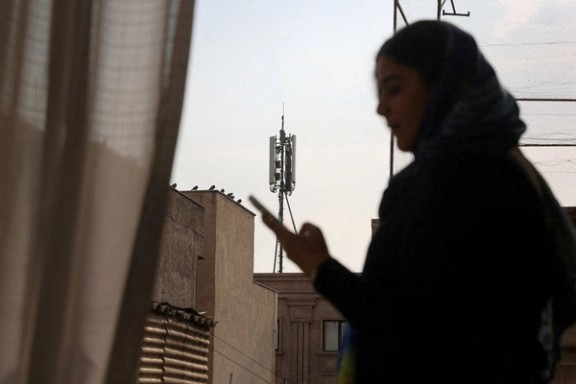 A telecommunications tower stands in the background as a woman in Tehran uses her phone on January 24, 2026.