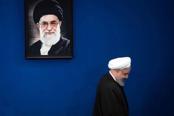Iran's former president Hassan Rouhani passing by a photo of Ali Khamenei
