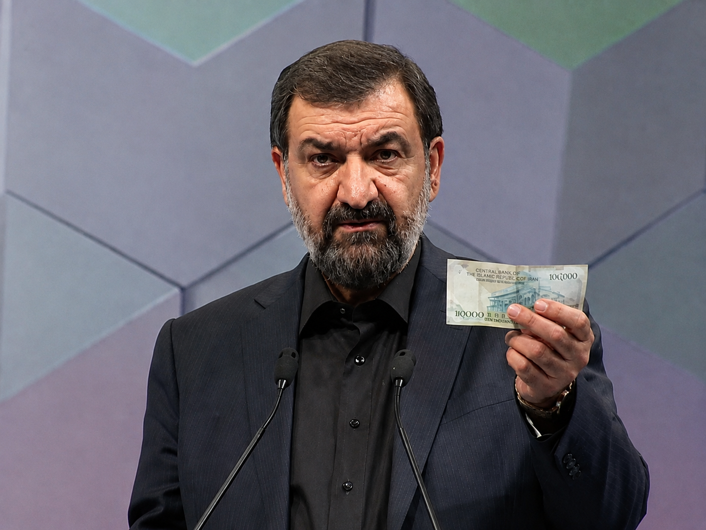 Mohsen Rezaei holds a banknote during a televised debate in Iran.