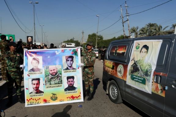 Members of an Iraqi Shiite armed group hold a banner during the funeral of their comrades who were killed in a US airstrike north of the city of Kirkuk, as their coffins are transported in vehicles, in Baghdad, Iraq December 4, 2023.