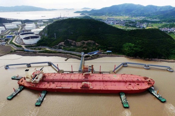 An aerial view shows tugboats helping a crude oil tanker to berth at an oil terminal, off Waidiao Island in Zhoushan, Zhejiang province, China.