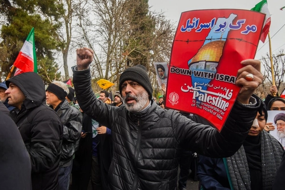 An Islamic Republic supporter holds an anti-Israel and pro-Palestine placard during a 2026 Quds Day rally in Karaj.