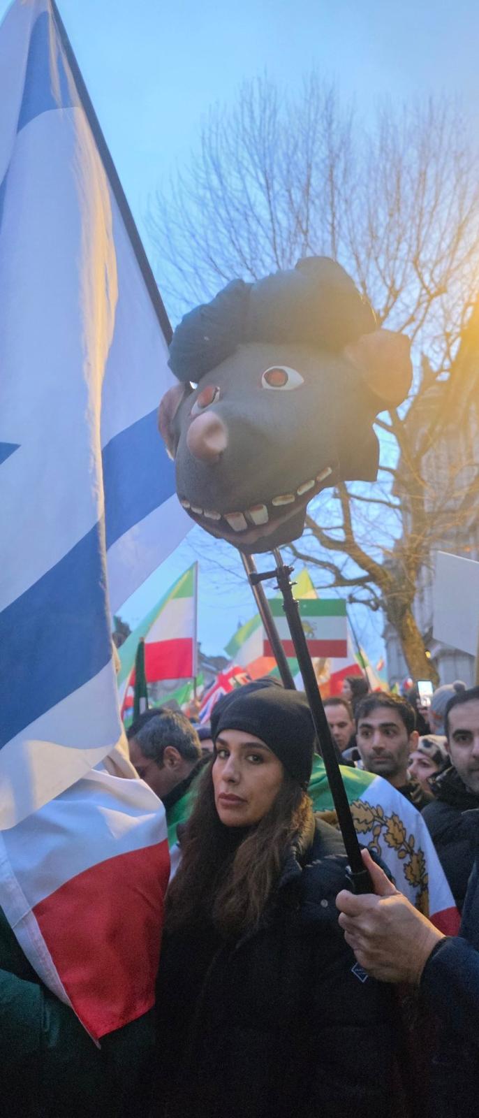 Protesters hold a rat’s head wearing a turban during a rally in support of protests in Iran