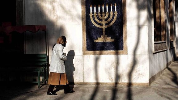 An Iranian woman walking past a Hanukkah menorah symbol