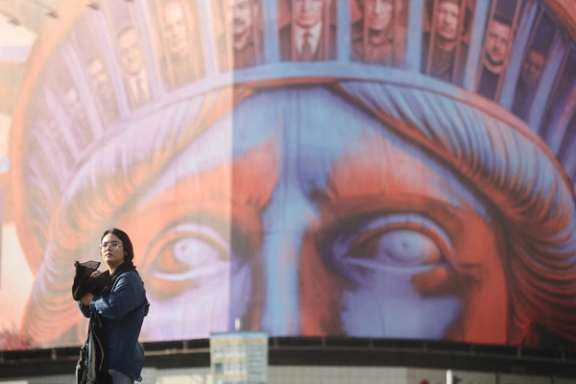 An Iranian woman walks past an anti-U.S. billboard on a street in Tehran, Iran, November 5, 2025.