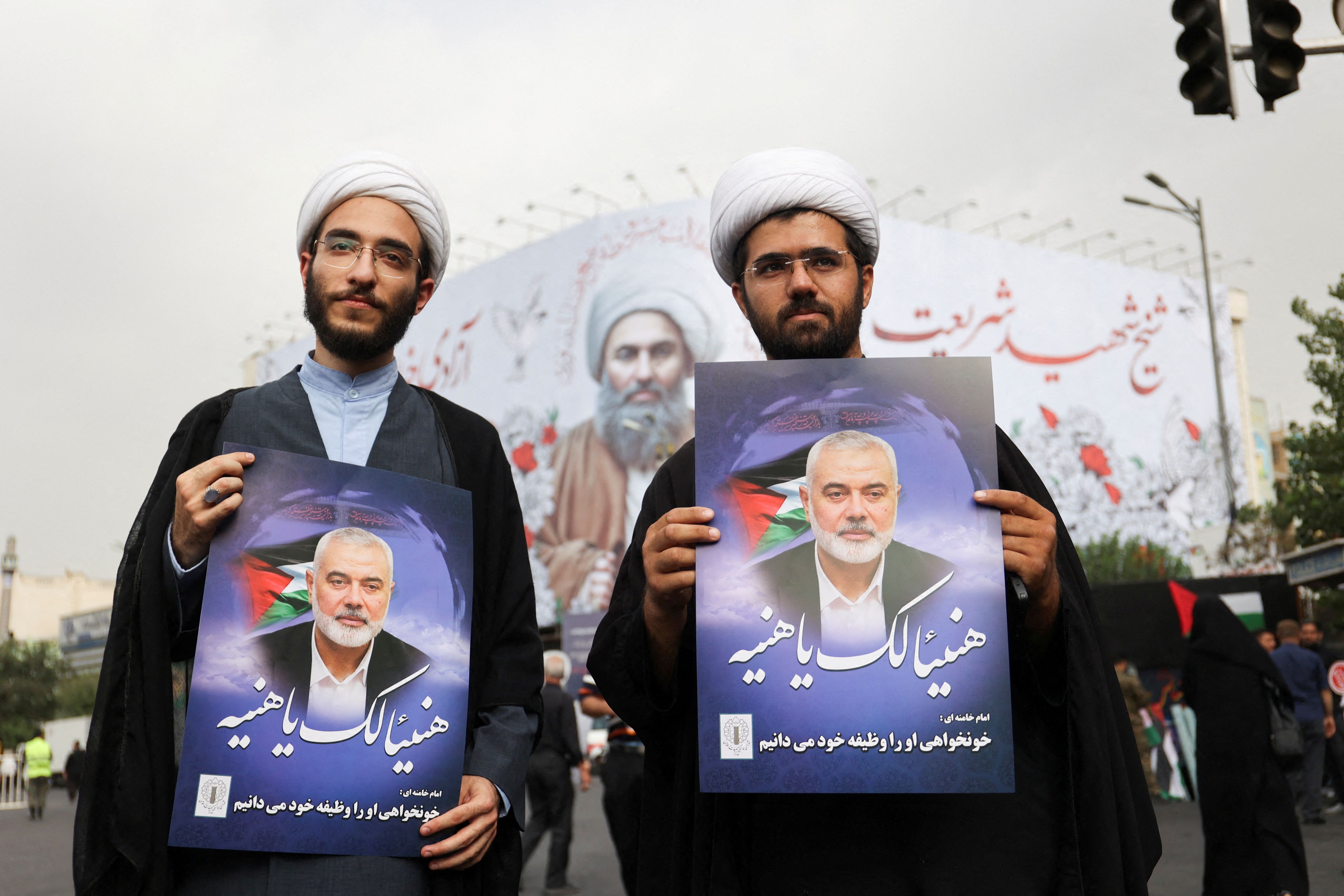 Two clerics hold posters of assassinated Hamas chief, Ismail Haniyeh during his funeral procession, in Tehran, Iran, August 1, 2024. 