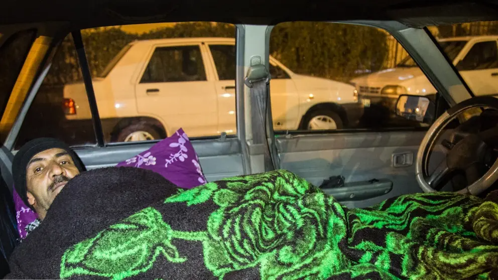 An internet taxi driver sleeping inside his car in Tehran