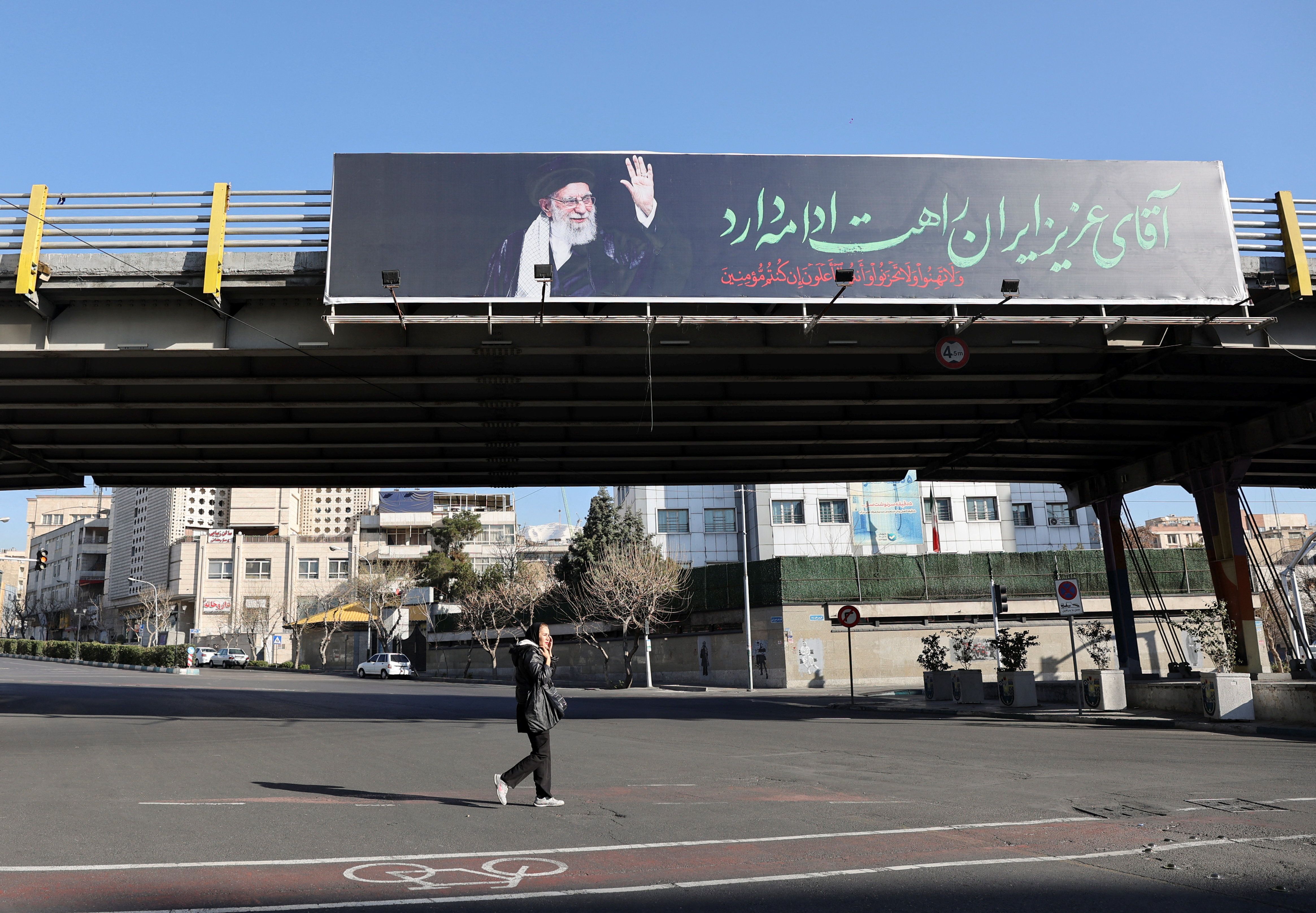 A woman walks past a billboard of Iran's late Supreme Leader Ali Khamenei on a street, after he was killed in Israeli and US strikes on Saturday, in Tehran, Iran, March 4, 2026. 