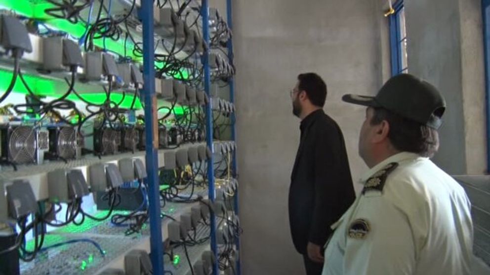 Iranian officials viewing a crypto mining set up discovered by police in 2021