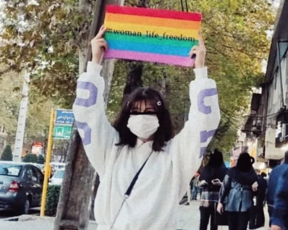 An Iranian protester holding a placard in support of the LGBTQ+ community and the Women, Life, Freedom movement