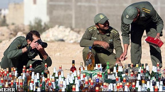 Iranian law enforcement forces before destroying alcoholic drinks they have confiscated