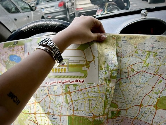 A driver in Iran relies on a printed map as widespread GPS disruptions render navigation apps unreliable.