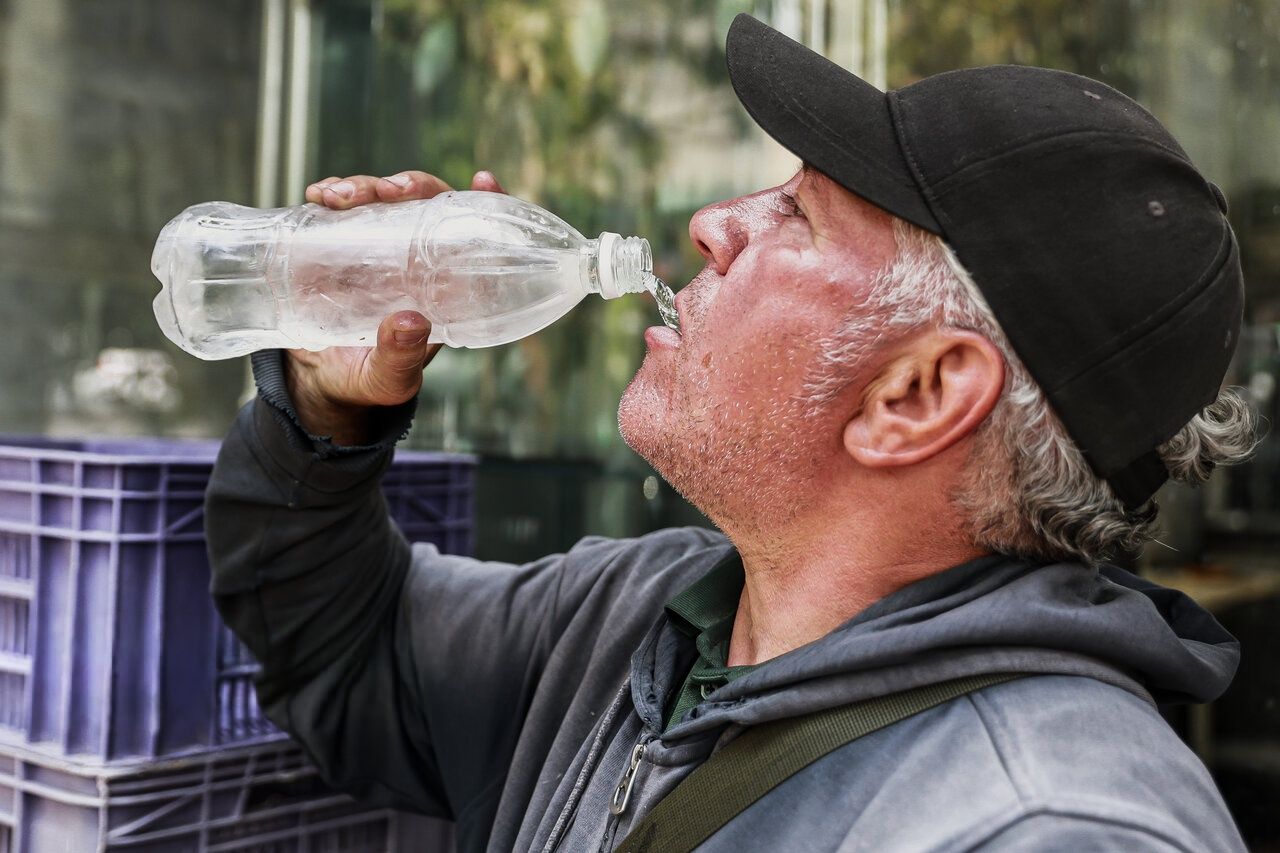A man drinks water from a plastic bottle, Tehran, Iran, July 30, 2025