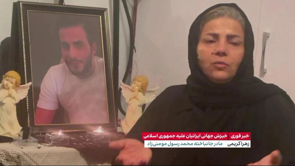 Mother of Mohammad Rasoul Momeni Rad next to a picture of her son