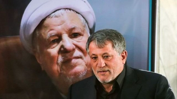 Mohsen Hashemi in front of a portrait of his father.