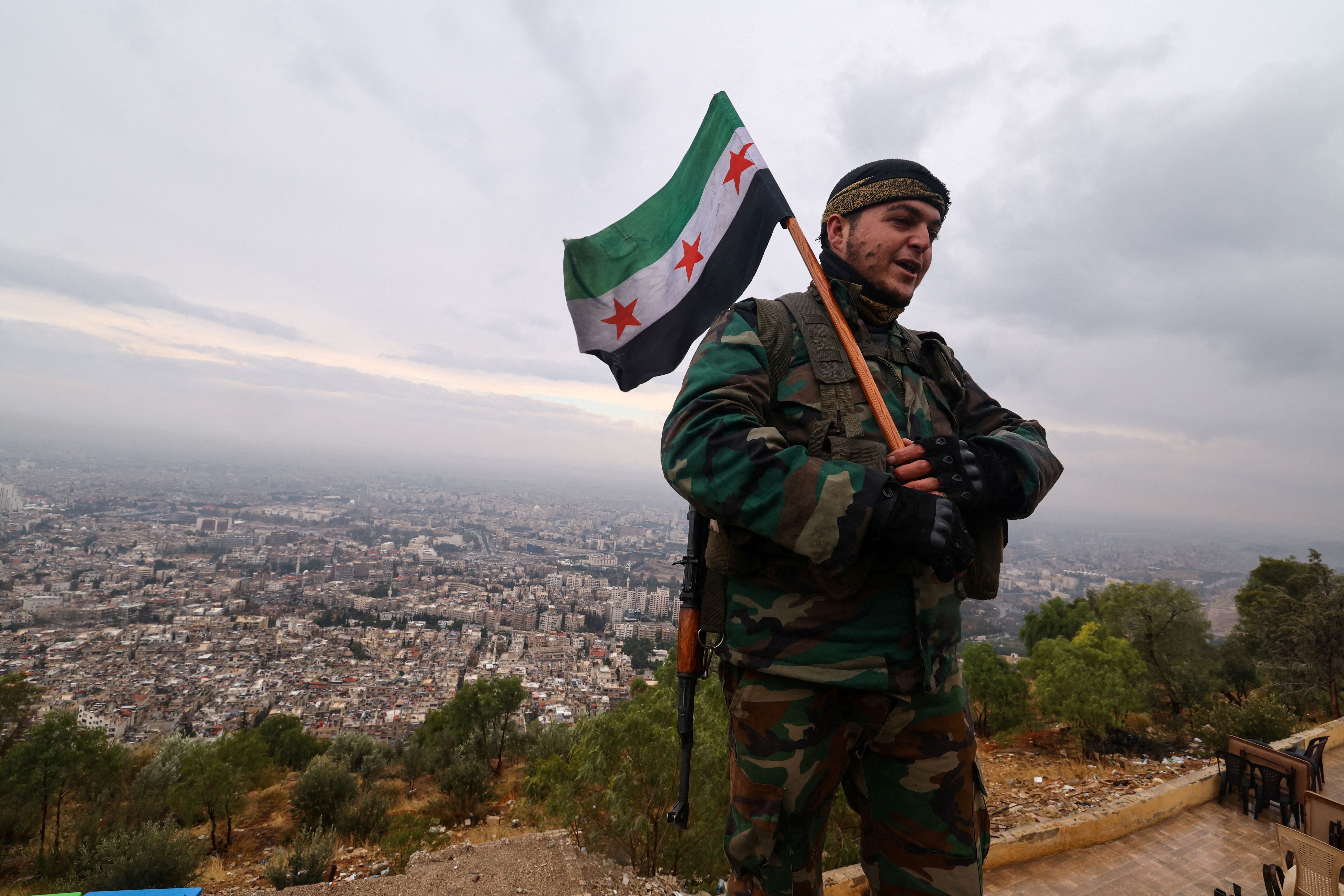 A fighter of the ruling Syrian body holds the flag adopted by the new rulers, as he visits Mount Qasioun, which was off-limits during the civil war, after the ousting of President Bashar al-Assad, in Damascus, Syria December 29, 2024. 