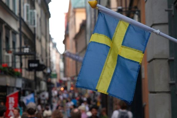 A Swedish flag hangs outside a store on a busy street as visitors walk past in the background in the old town of Stockholm, Sweden, July 14, 2023