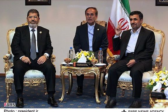 Former president of Iran Mahmoud Ahmadinejad (right) flashes a victory sign during a meeting with his Egyptian counterpart Mohammed Morsi (left) on the sidelines of the Non-Aligned Movement summit in Tehran, on August 30, 2012.