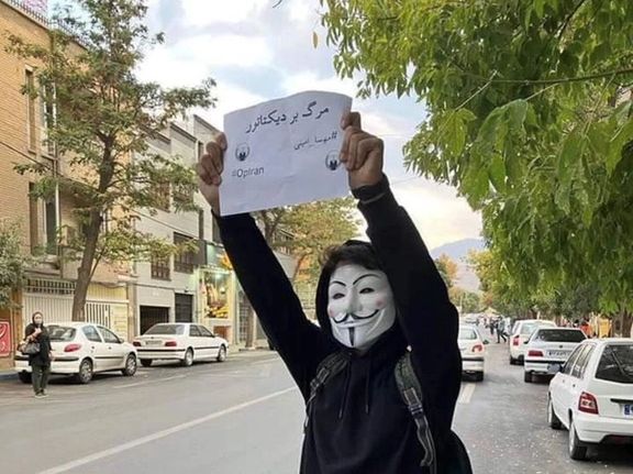 A protester in Tehran holding up a sign that says, "Death to the dictator". October 2022