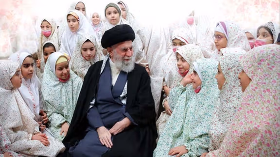 Supreme Leader Ali Khamenei meets with a group of Iranian schoolgirls in Tehran, an image featured in the new textbook “Defending Our Iran.” (undated)
