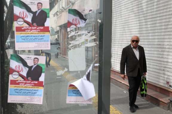 An Iranian man walks past campaign posters for the parliamentary election in Tehran, Iran, February 24, 2024.
