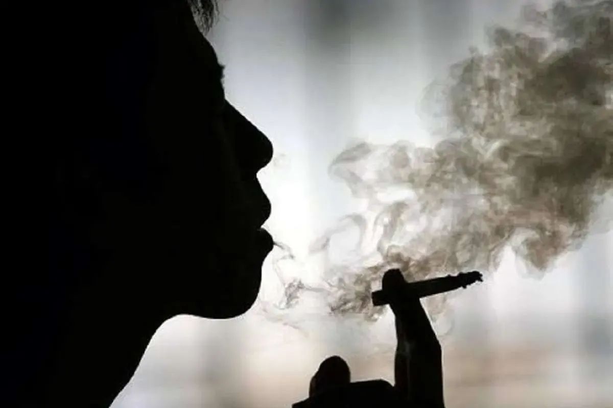 A person exhales smoke while holding a cigarette, as reports point to changing patterns of drug use among young Iranians.