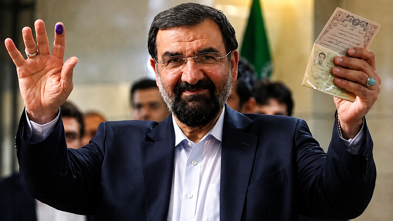 Mohsen Rezaei displays his identification document and inked finger as he registers to run in Iran’s presidential election.