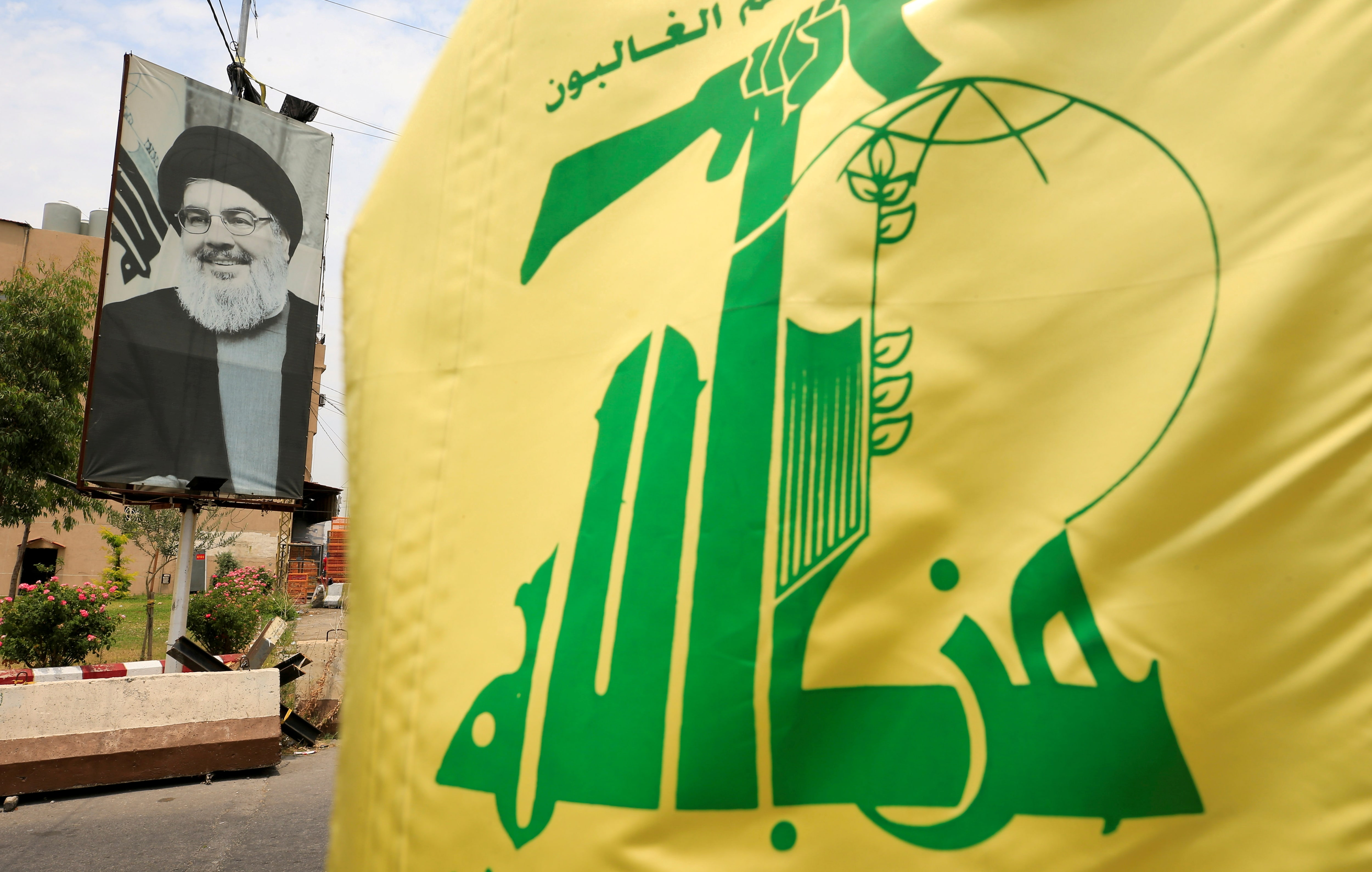 A Hezbollah flag and a poster depicting Hezbollah's then leader Hassan Nasrallah are pictured along a street, near Sidon, Lebanon July 7, 2020. 