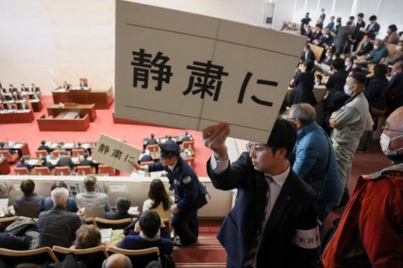 افسران امنیتی در نشست پارلمان محلی پلاکاردهایی در دست داشتند که روی آنها نوشته شده بود: «لطفا سکوت را رعایت کنید»