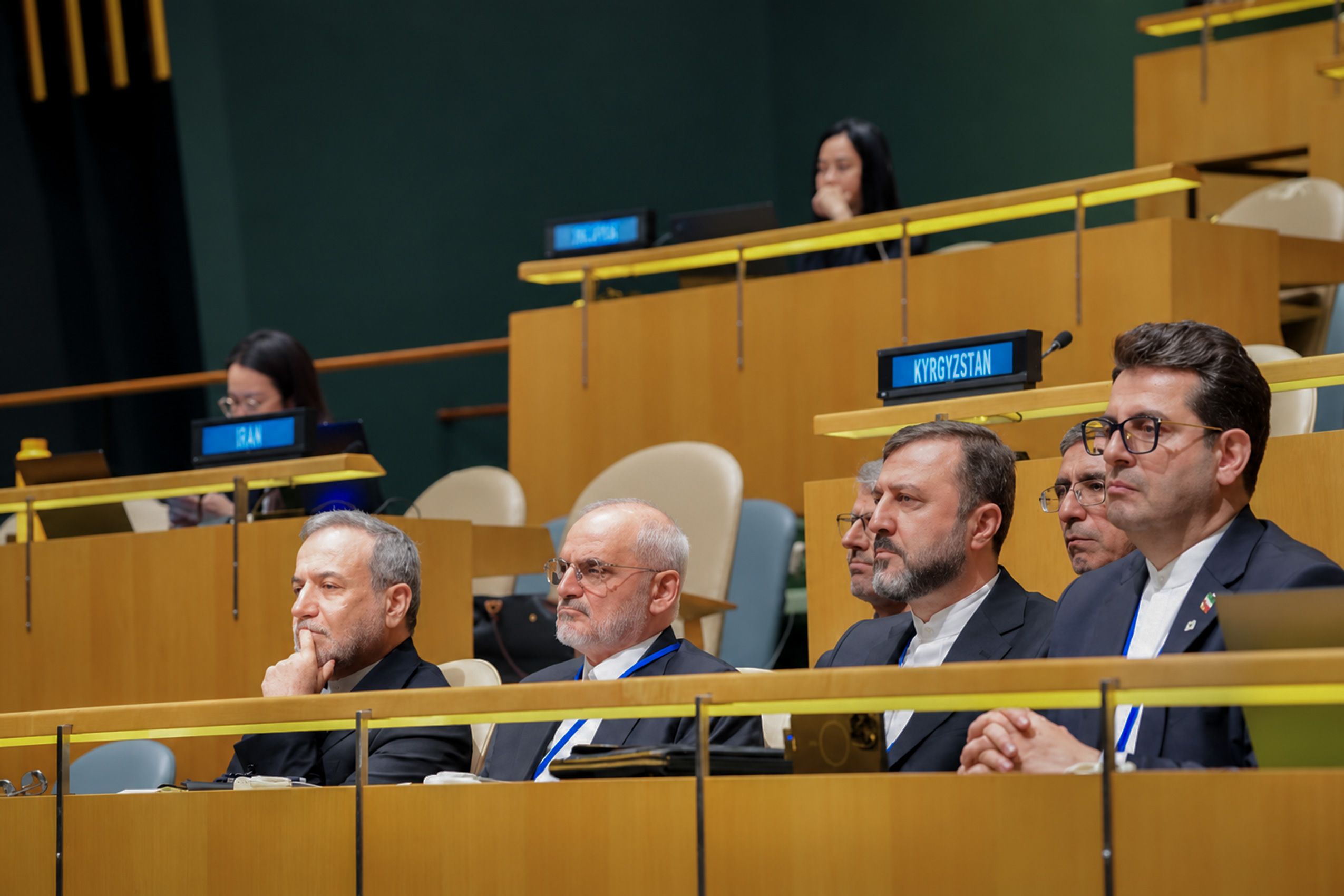 Foreign Minister Abbas Araghchi (left) and other members of Iran's delegation in the General Assembly hall listen as President Masoud Pezeshkian speaks in New York on September 23, 2026. 